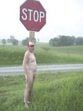standing naked on a rural highway next to a stop sign