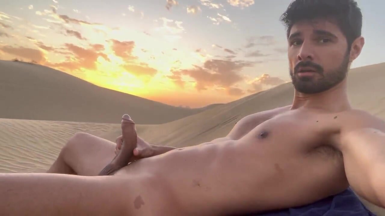 Hot uncut hunk lies in the desert sand and jerks off