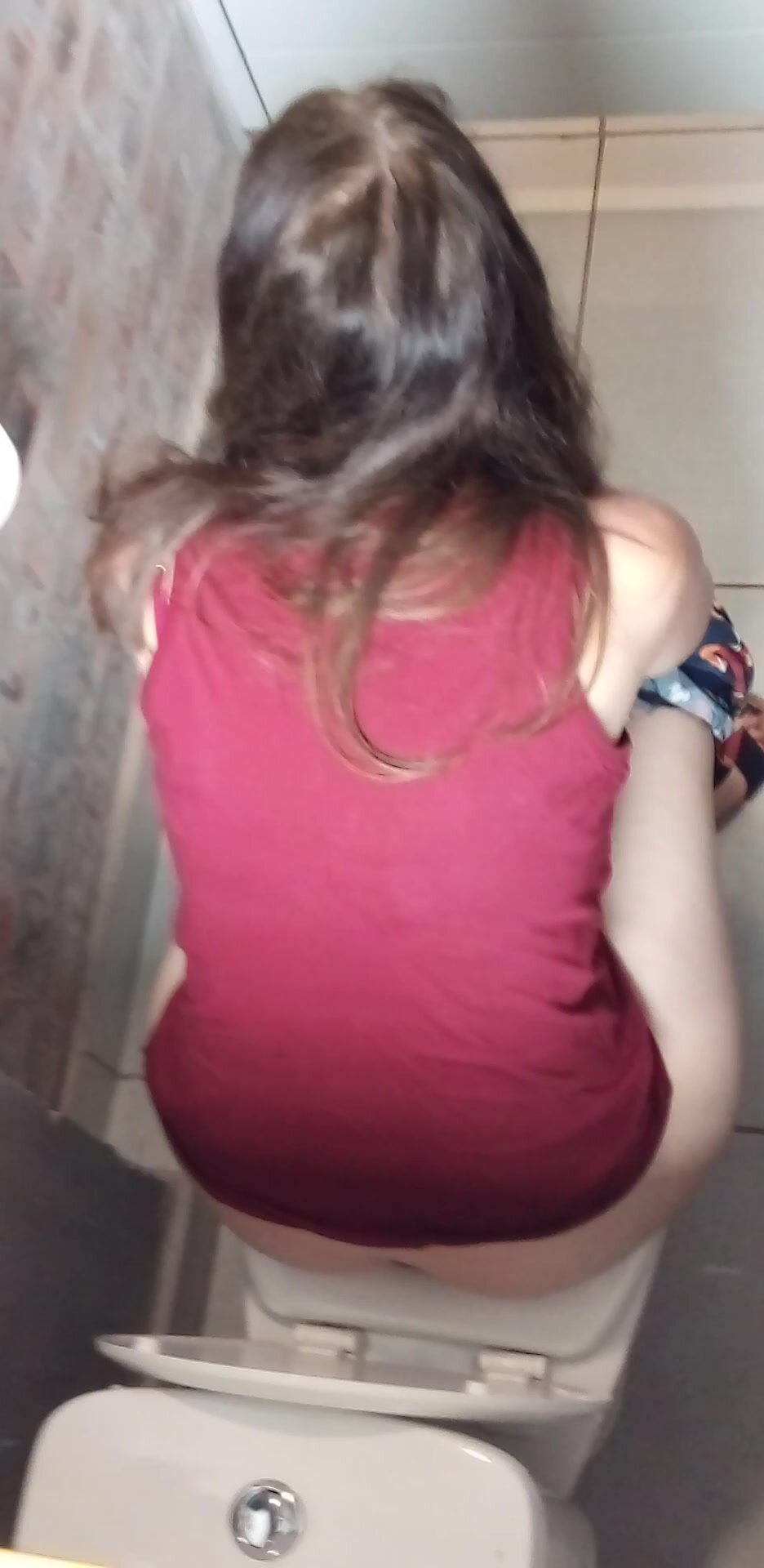 Brunette haired lady shitting in toilet