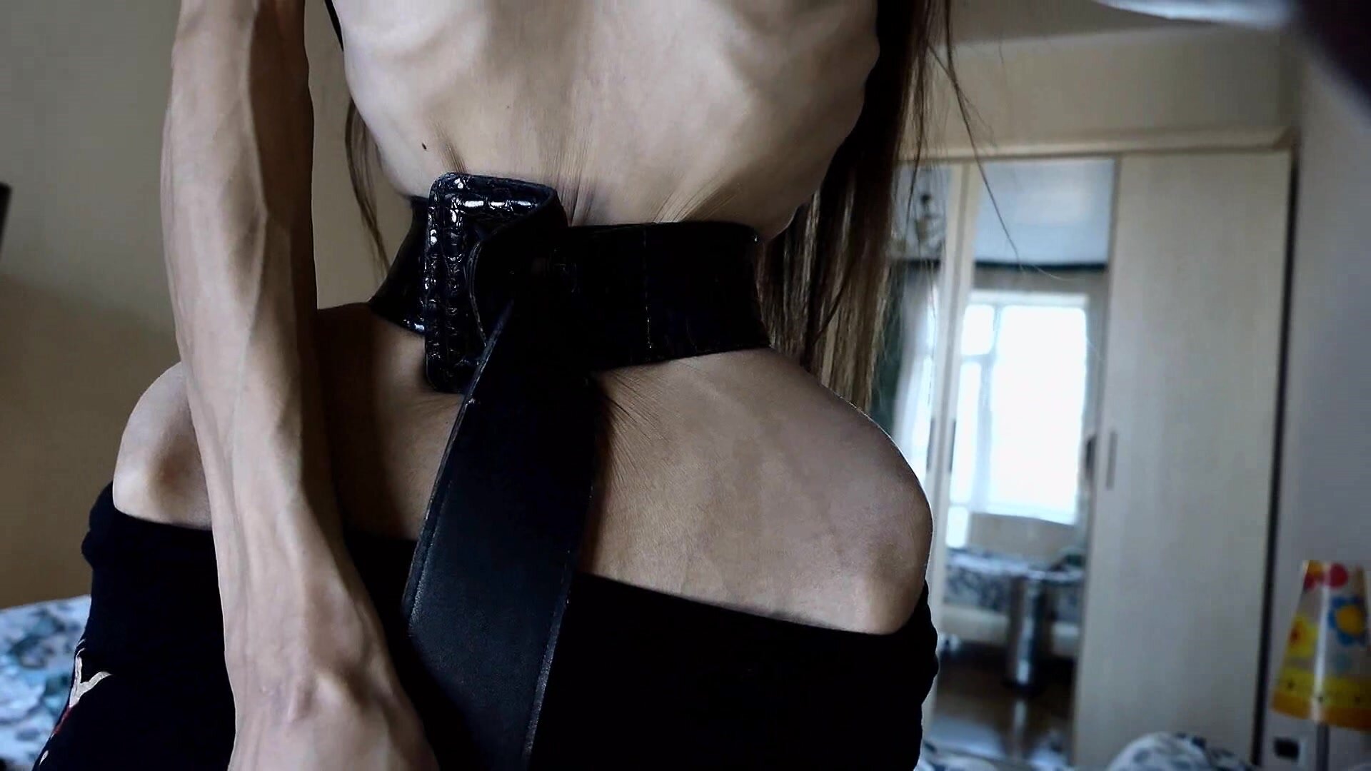 Anorexic Tightening a belt around her tiny waist.