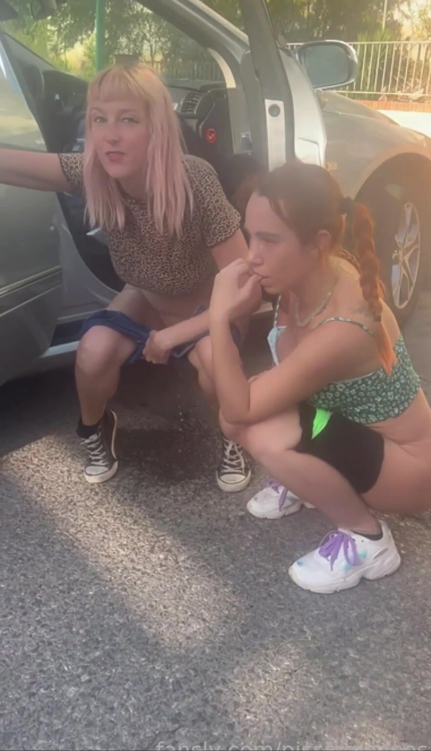 two girls pee in parking lot
