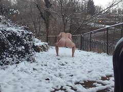 Nudist girl pisses in the snow by a public road