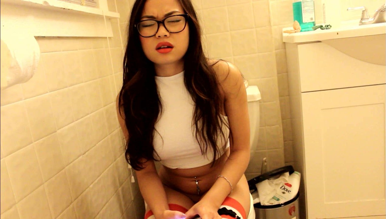 A Young Lady With Glasses Sitting on The Toilet Farting