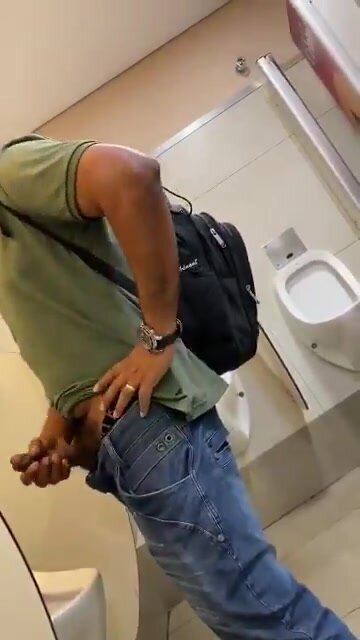 Black guy stroking thick cock in the toilet