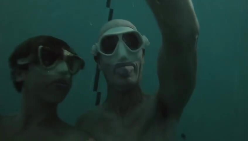 Masked freedivers diving deep underwater in tank