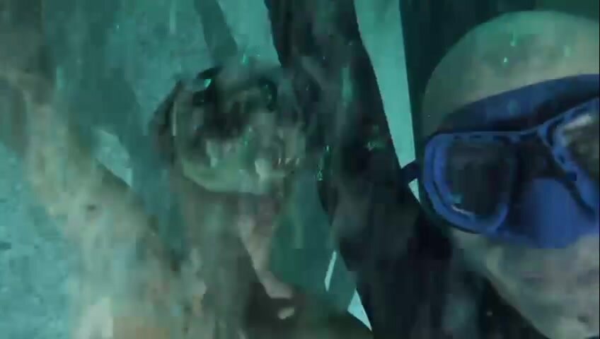 Masked freedivers diving deep underwater in a tank