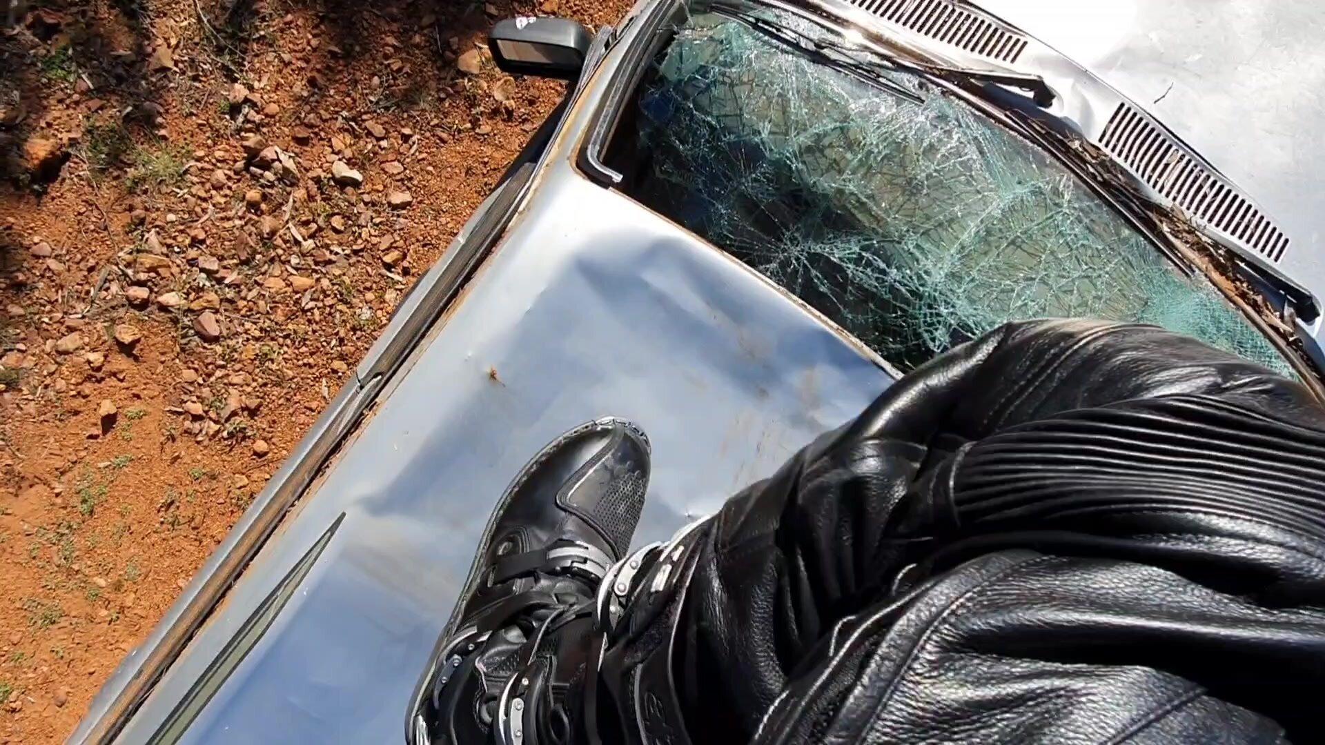 Leather biker's POV of boots stomping old car