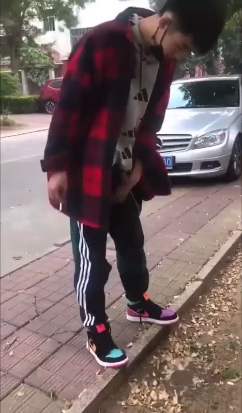 Asian guy pissing by the sidewalk