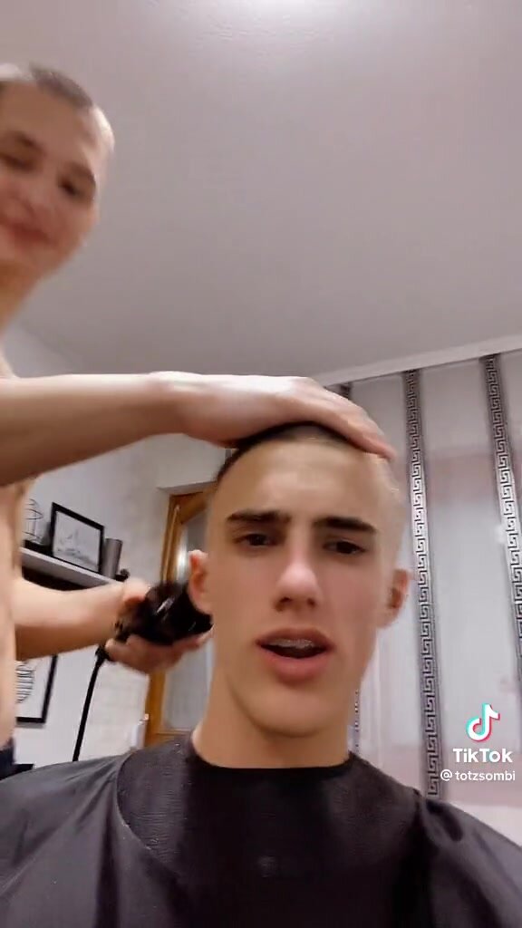 shirtless barber gives short buzzcut haircut with brace