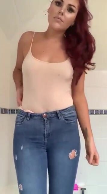 Red-hair girl wetting jeans in the bathroom