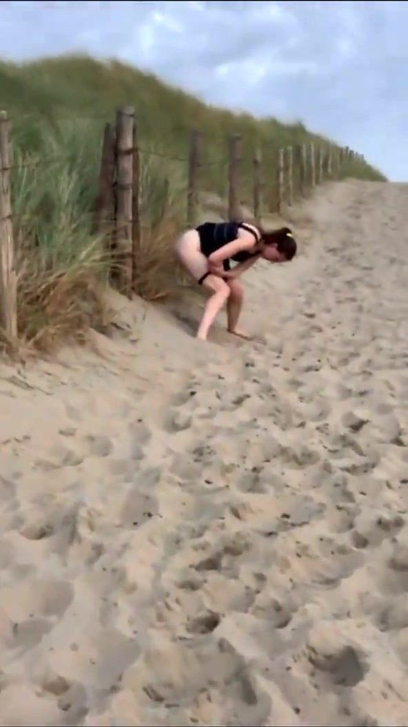 Lady pops squat in the sand at the end of beach