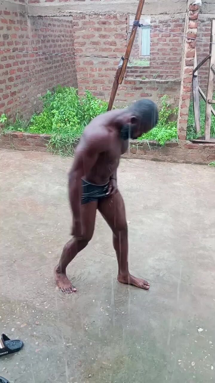 Black African male playing muscles under the rain