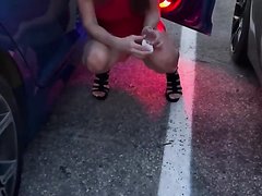 Woman takes a leak behind car door in parking lot