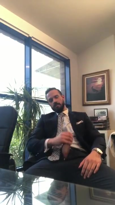 suited guy jerks in his office