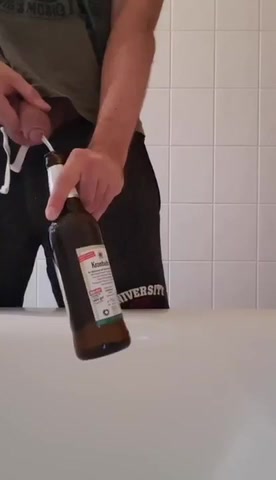 Guy pissing in a beer bottle