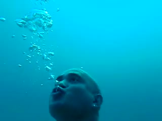 Bald freediver ripping mask underwater