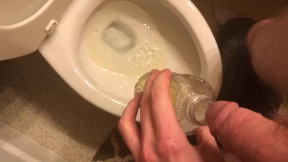 Young guy pissing in a plastic bottle