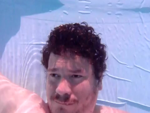 Barefaced guy breatholding underwater in pool