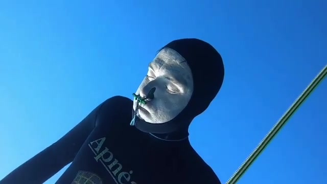 Barefaced freediver going deep underwater
