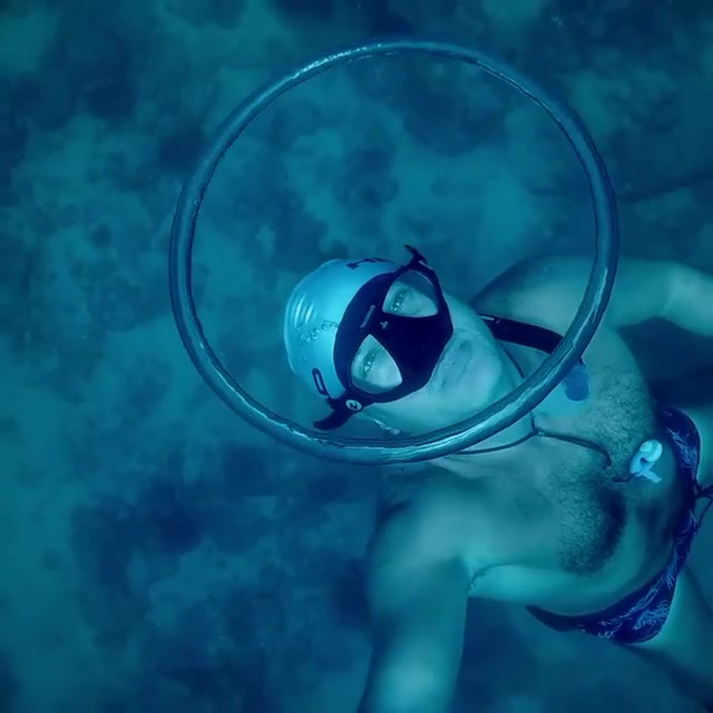 Barechest freediver blowing air ring underwater