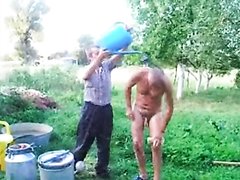 Grandpa taking a shower in the farm! Son helps and grandson films!