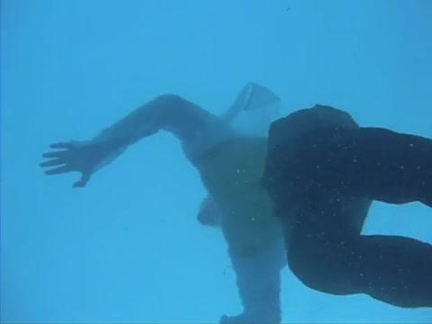 Clothed guy swimming barefaced underwater