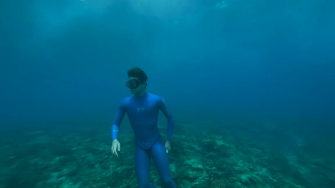 French freediver breatholding underwater in tight wetsuit