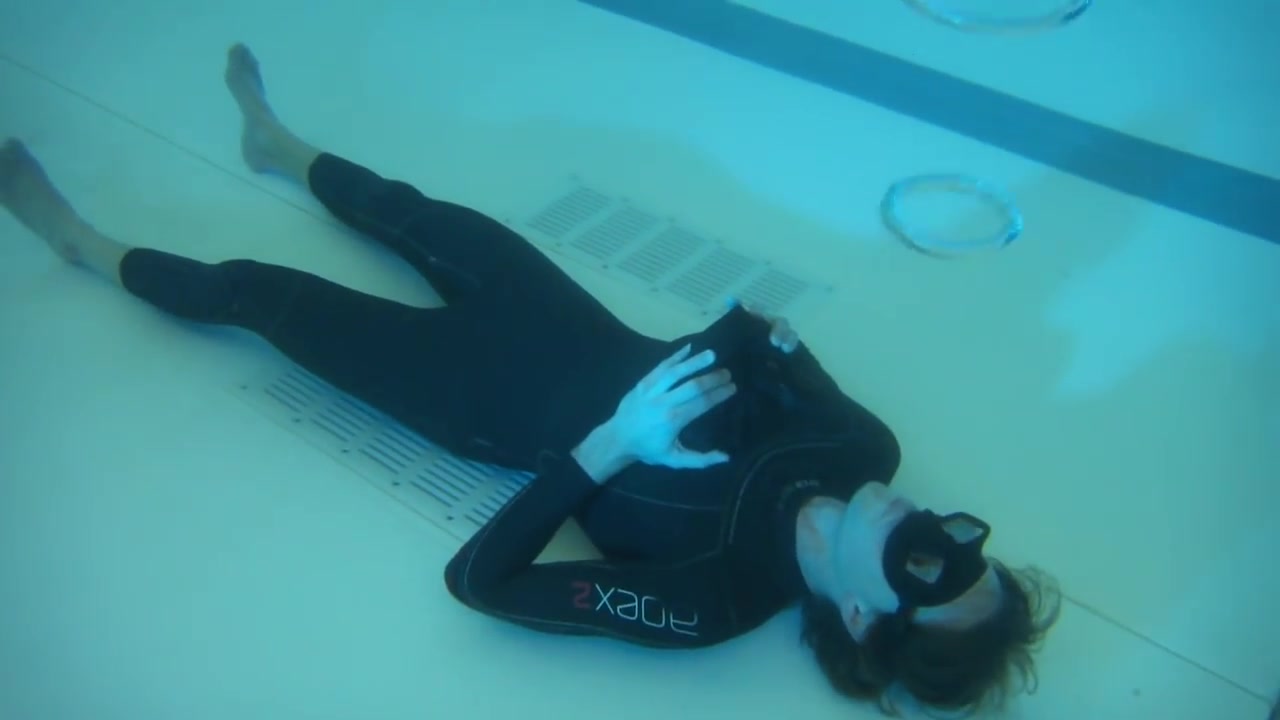 Blowing bubble rings underwater in tight wetsuit