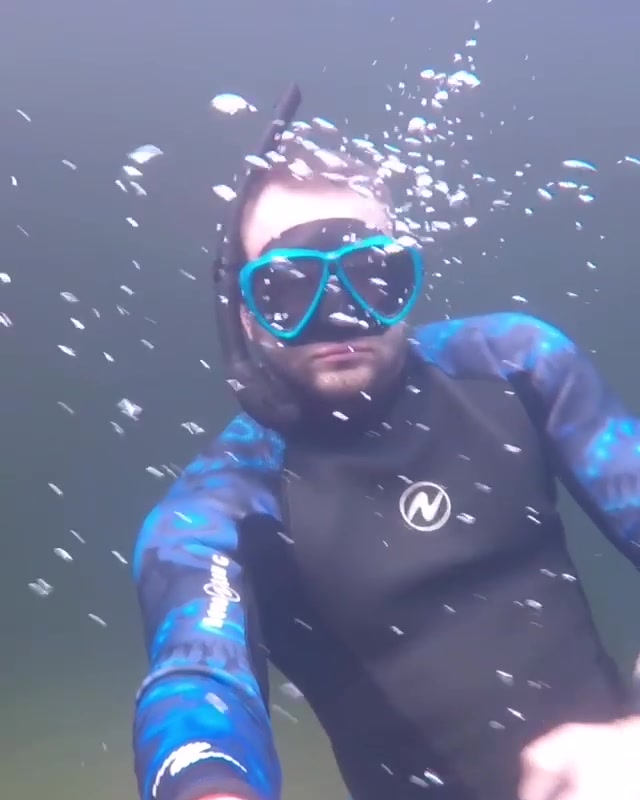 Freediver breatholding underwater in wetsuit