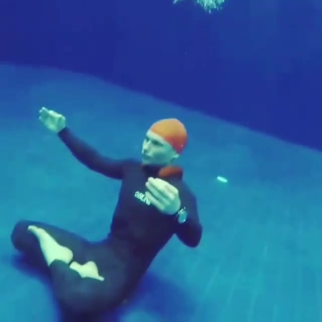 Underwater barefaced yoga in wetsuit