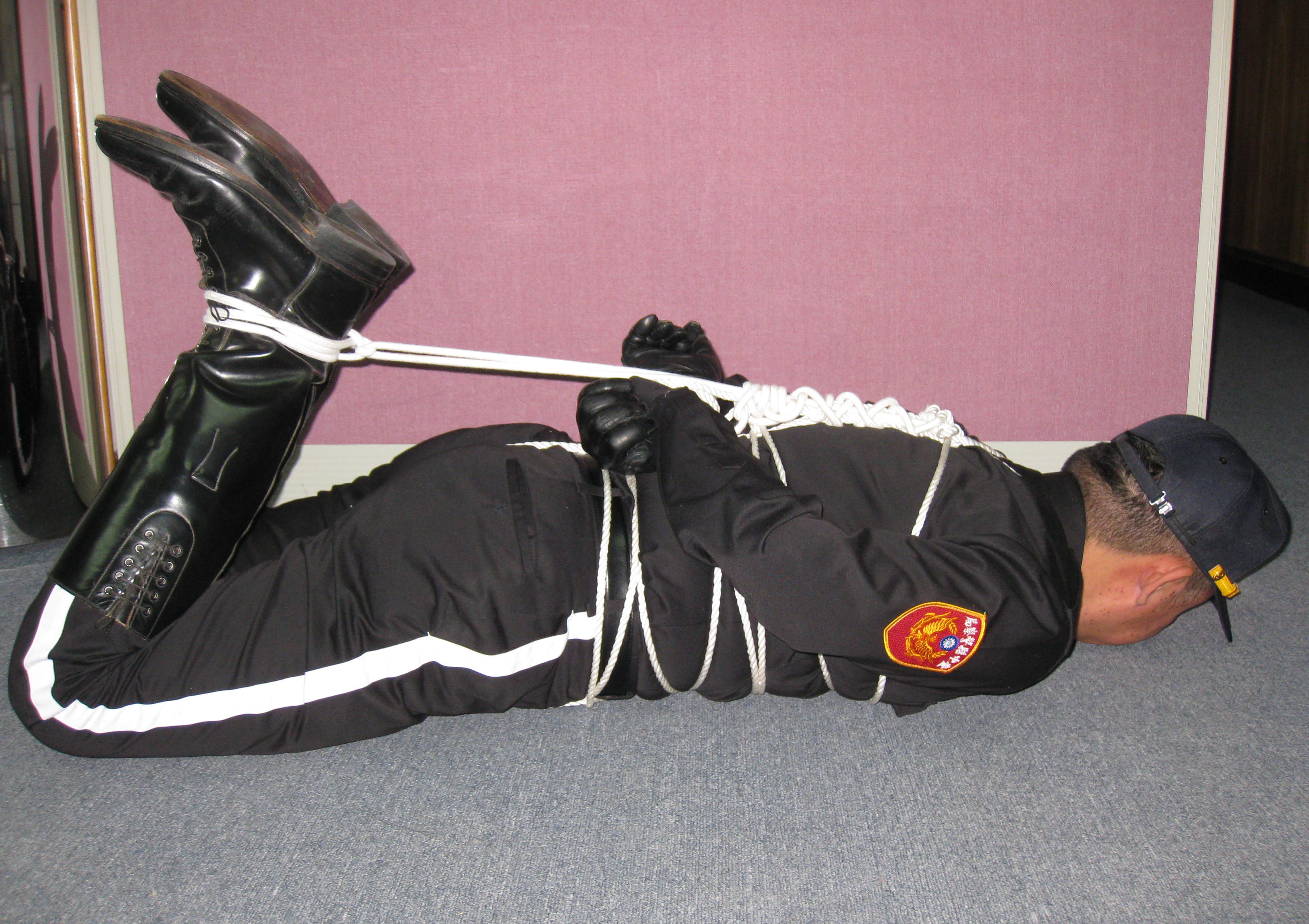 Officer in boots and gloves hogtied