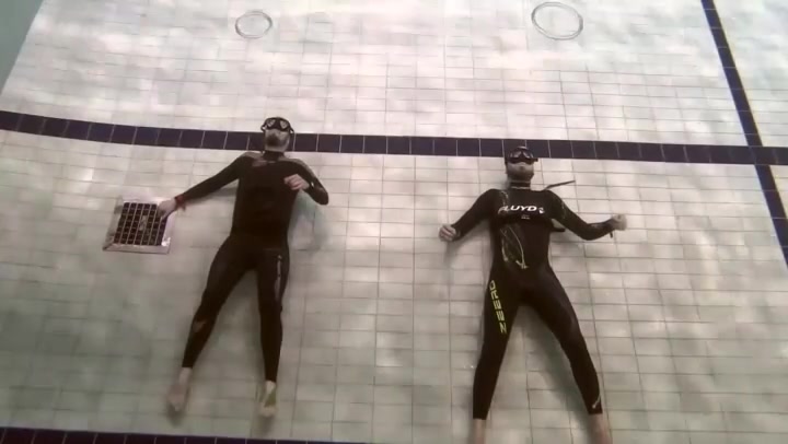 Buddies in wetsuit blowing bubbles underwater