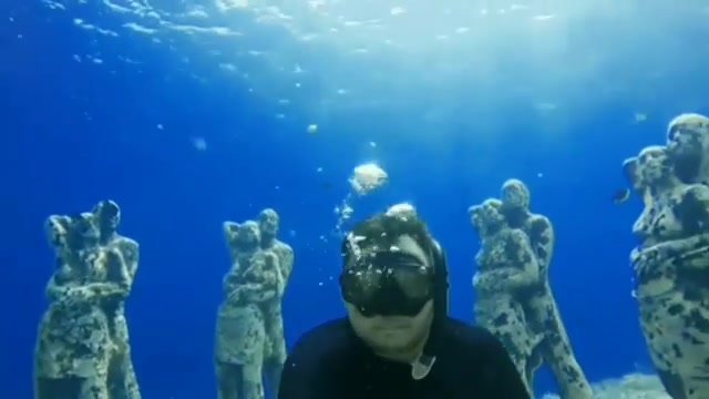 Cheeky freediver breatholding underwater in wetsuit