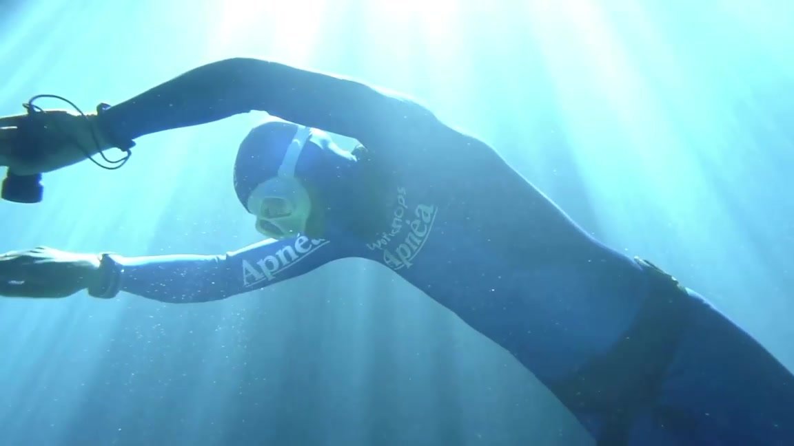 Breatholding underwater in tight blue wetsuit