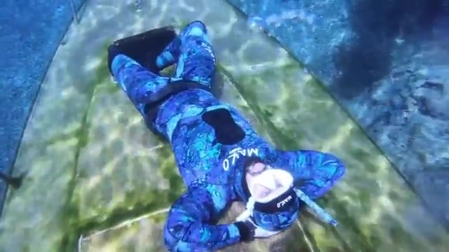 Blowing bubbles underwater in blue wetsuit