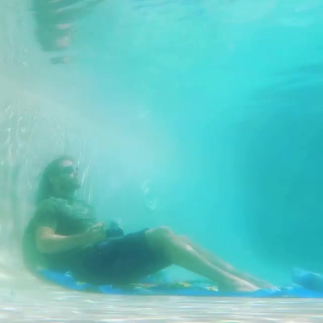 Clothed hunk breatholding underwater in pool