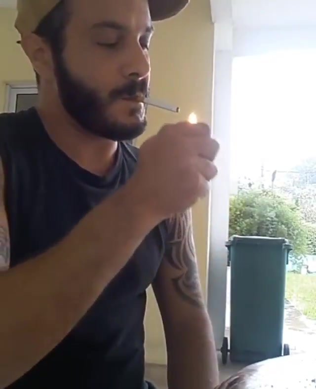 Cocky bearded smoker spits and smirks while smoking