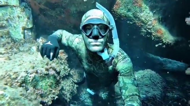 Hottie breatholds underwater in camo wetsuit