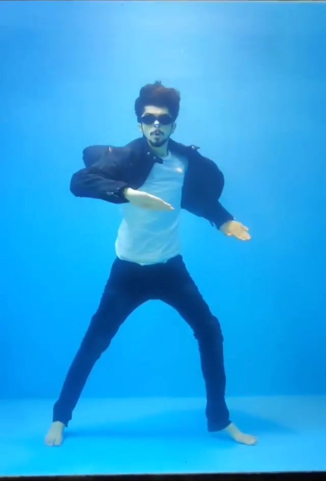 Clothed indian singing barefeet underwater in tank