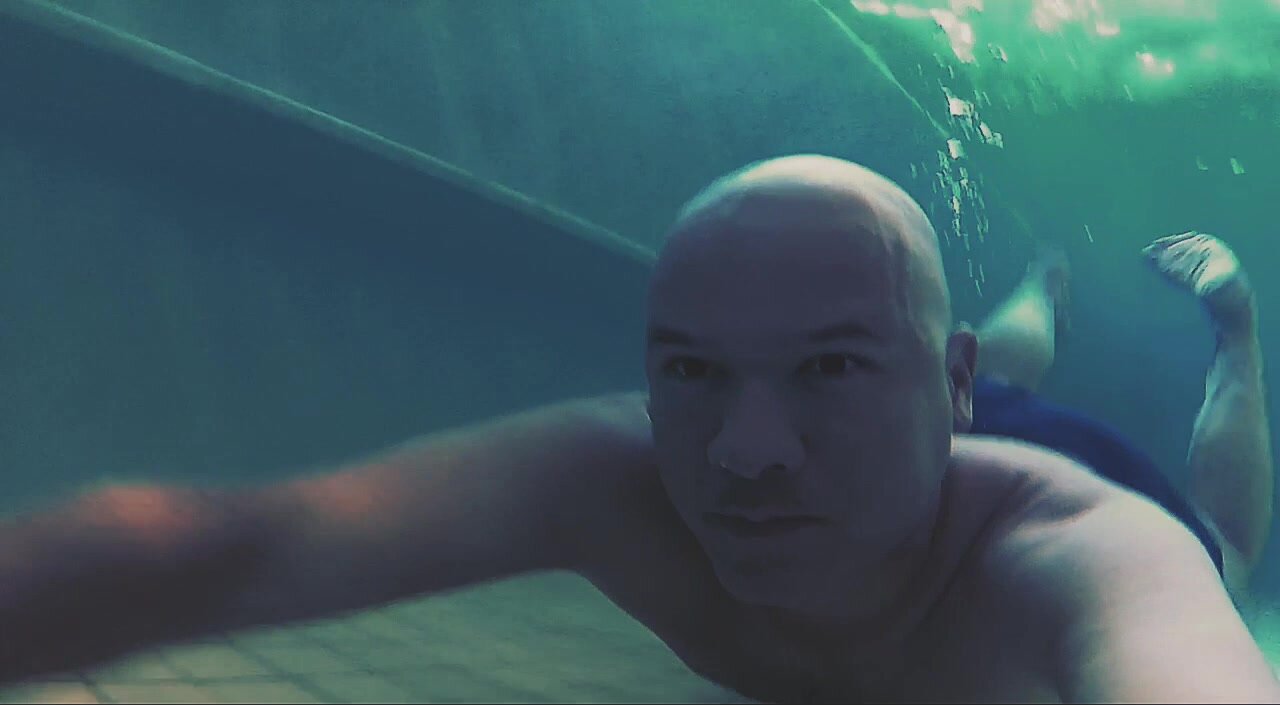 Bald barefaced guy swimming underwater