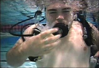 Beefy scubadiver exhaling air barefaced underwater