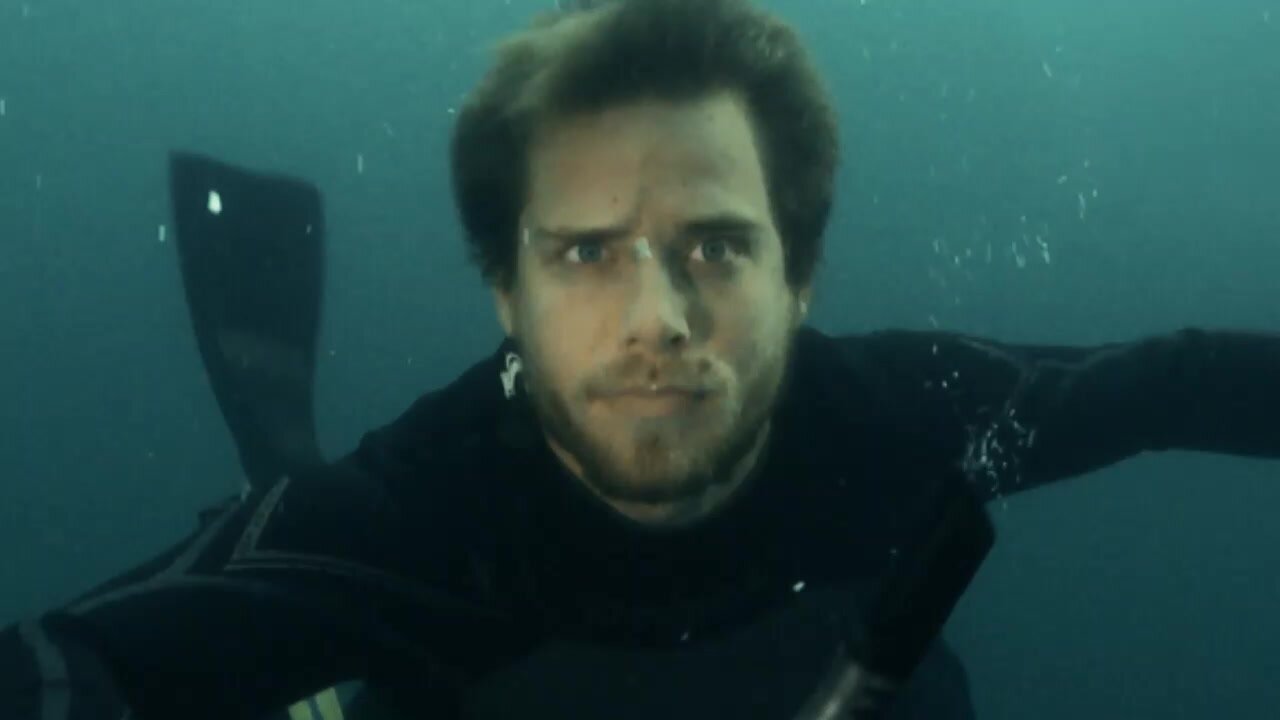 Underwater barefaced actor in wetsuit