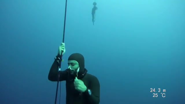 Barefaced freediver underwater in tight wetsuit