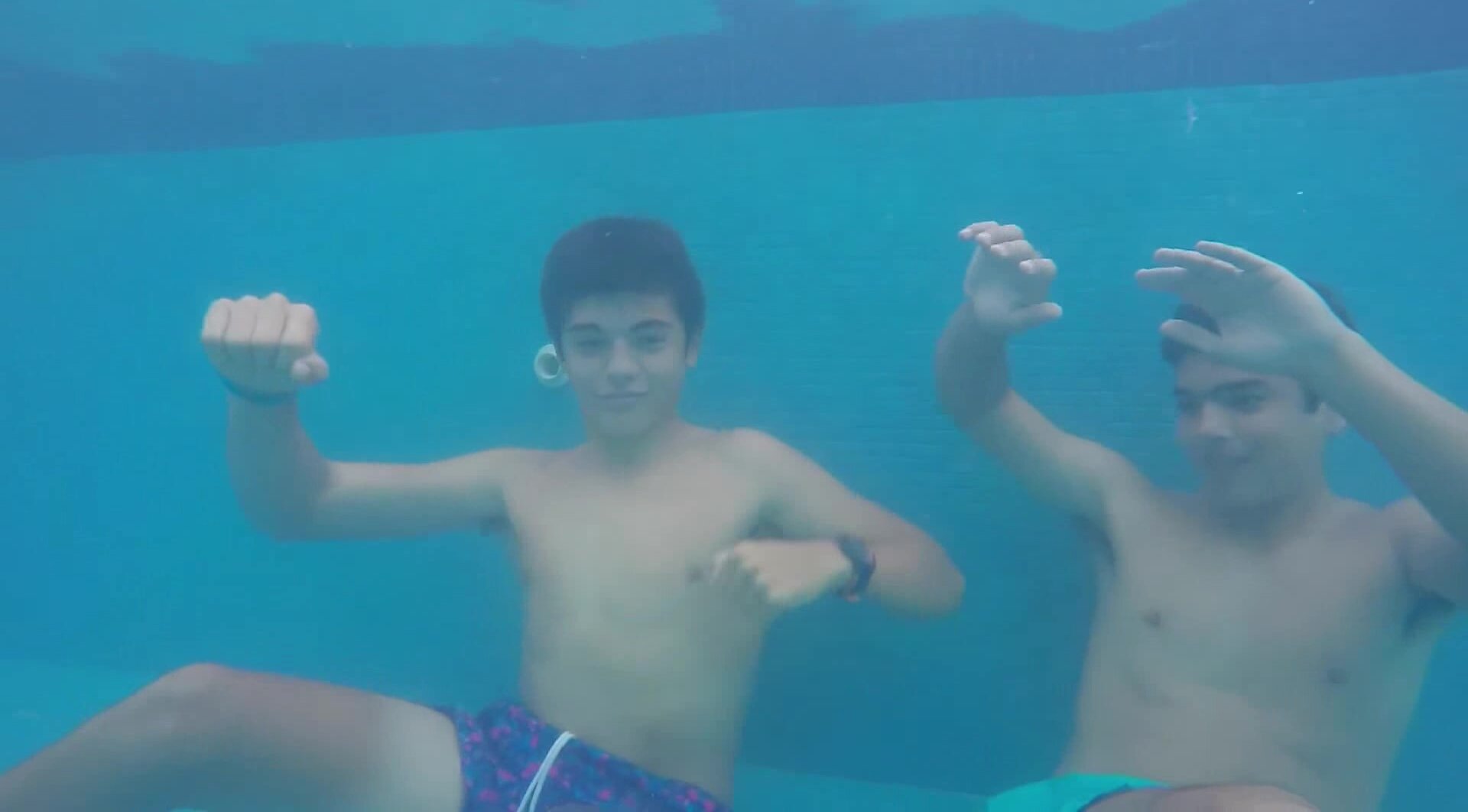 Barefaced buddies dancing underwater in pool