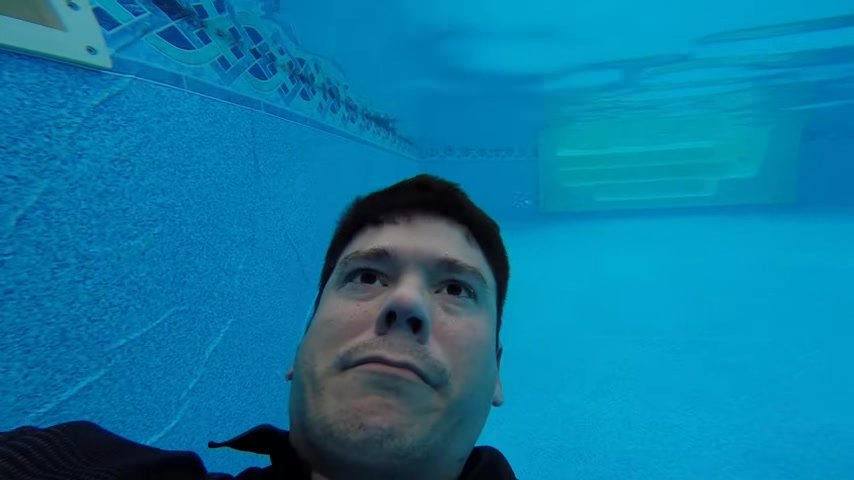 Clothed and barefaced underwater in pool
