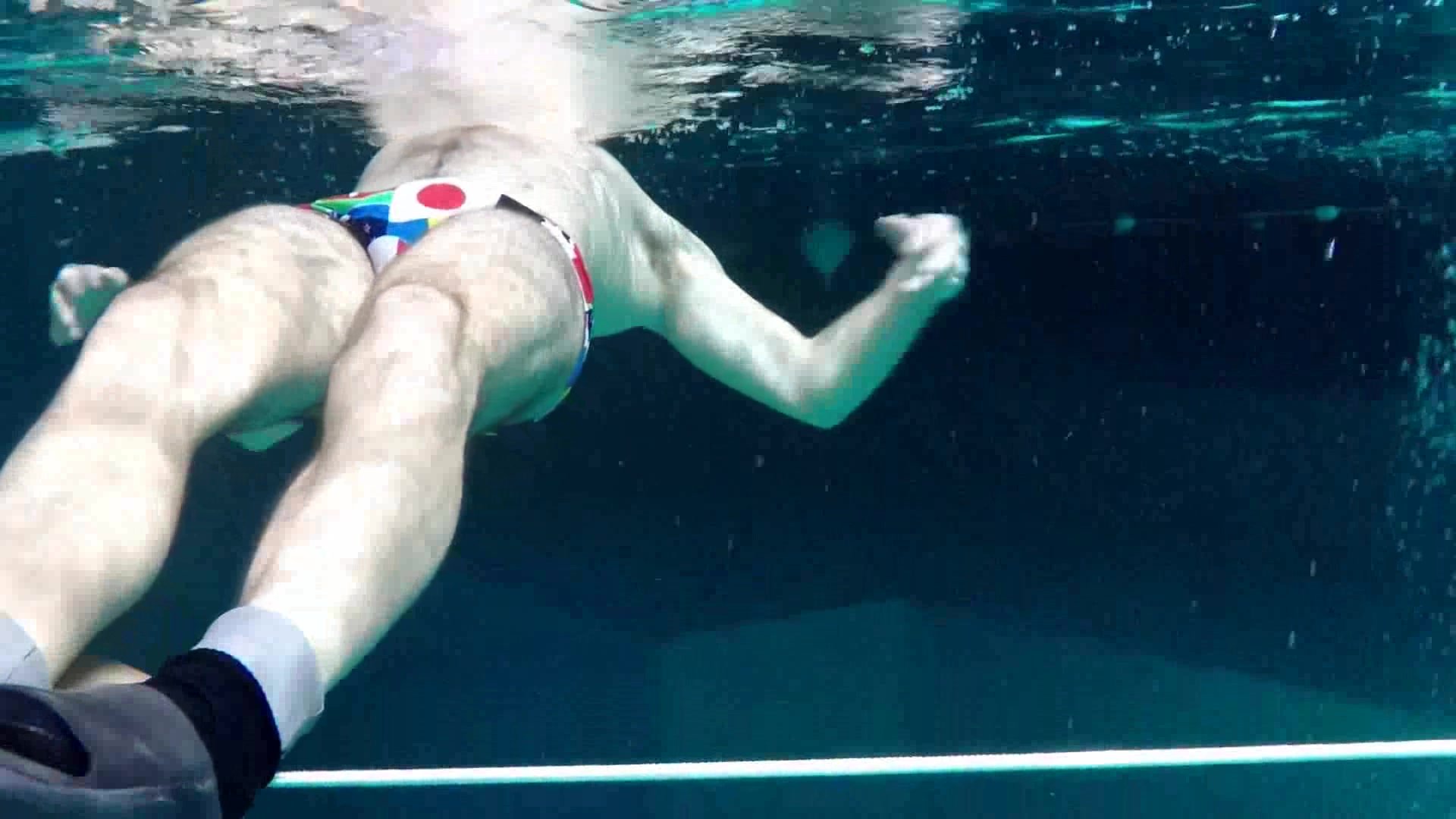 French freediver breatholing underwater in speedo