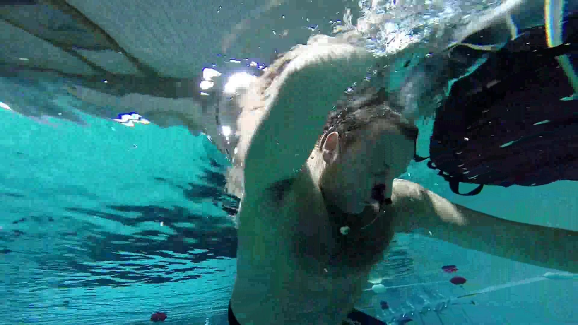 Beefy speedo guy diving deep underwater barefaced
