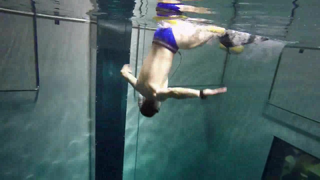 Freediving deep underwater in blue speedo