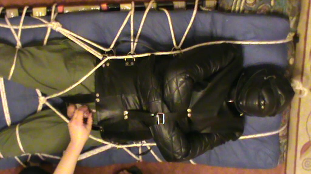 Restrained slave is in the leather straitjacket