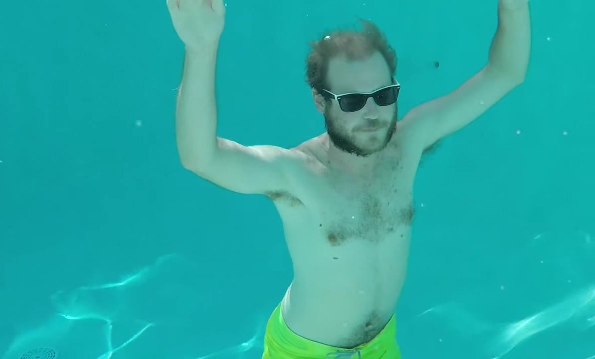 Hairy guy underwater with shades in slowmotion